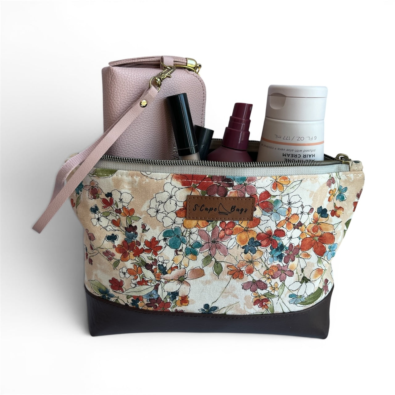 Floral-patterned handbag with cosmetic items on a white background